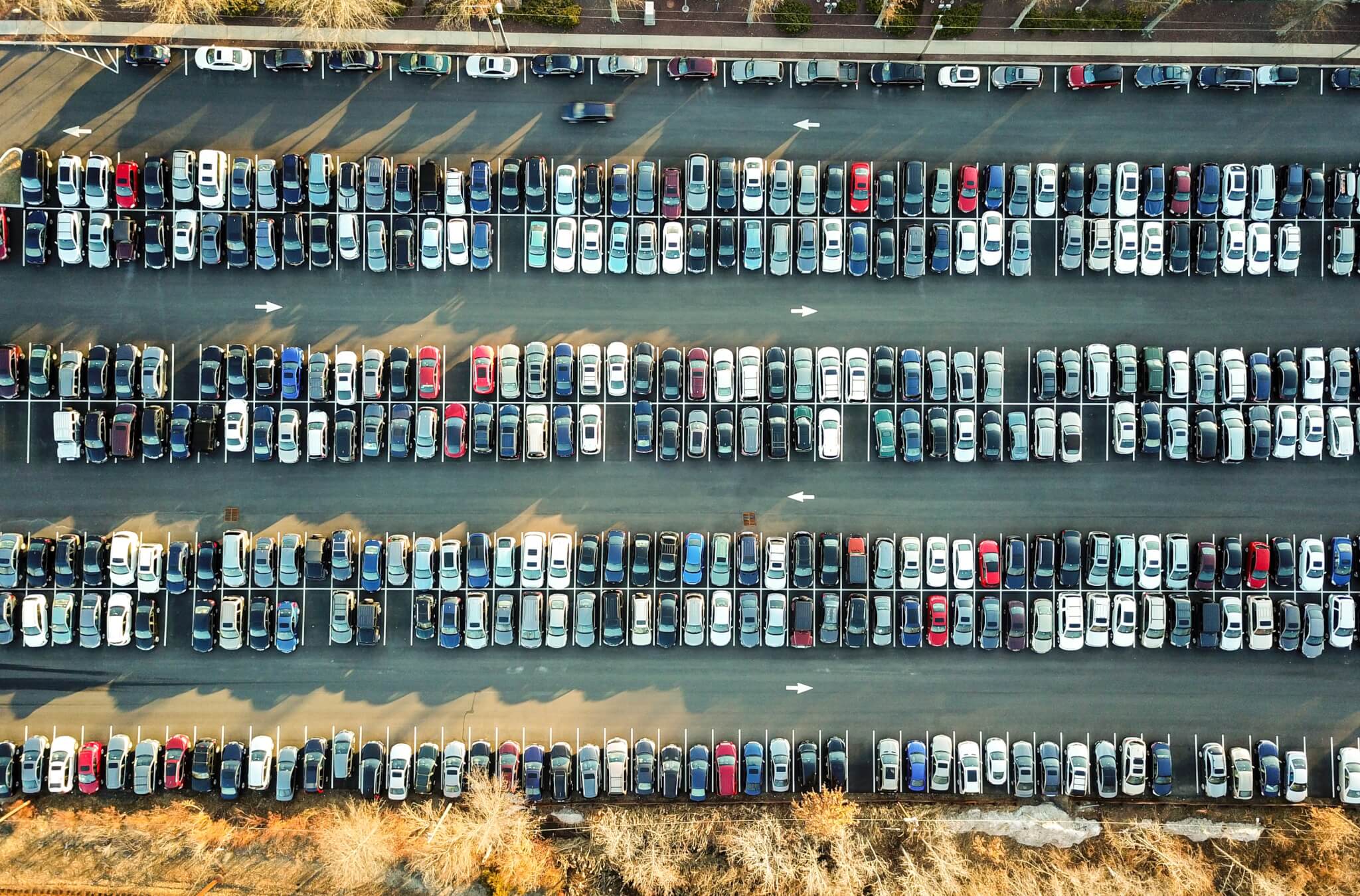 Aerial view of large parking lot with hundreds of cars arranged in rows